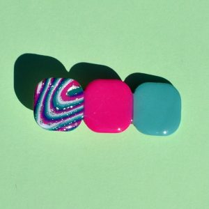 Barrette composée de trois carrés retro, un motif "à la dérive des astres", un rose vif, un vert vague marine.