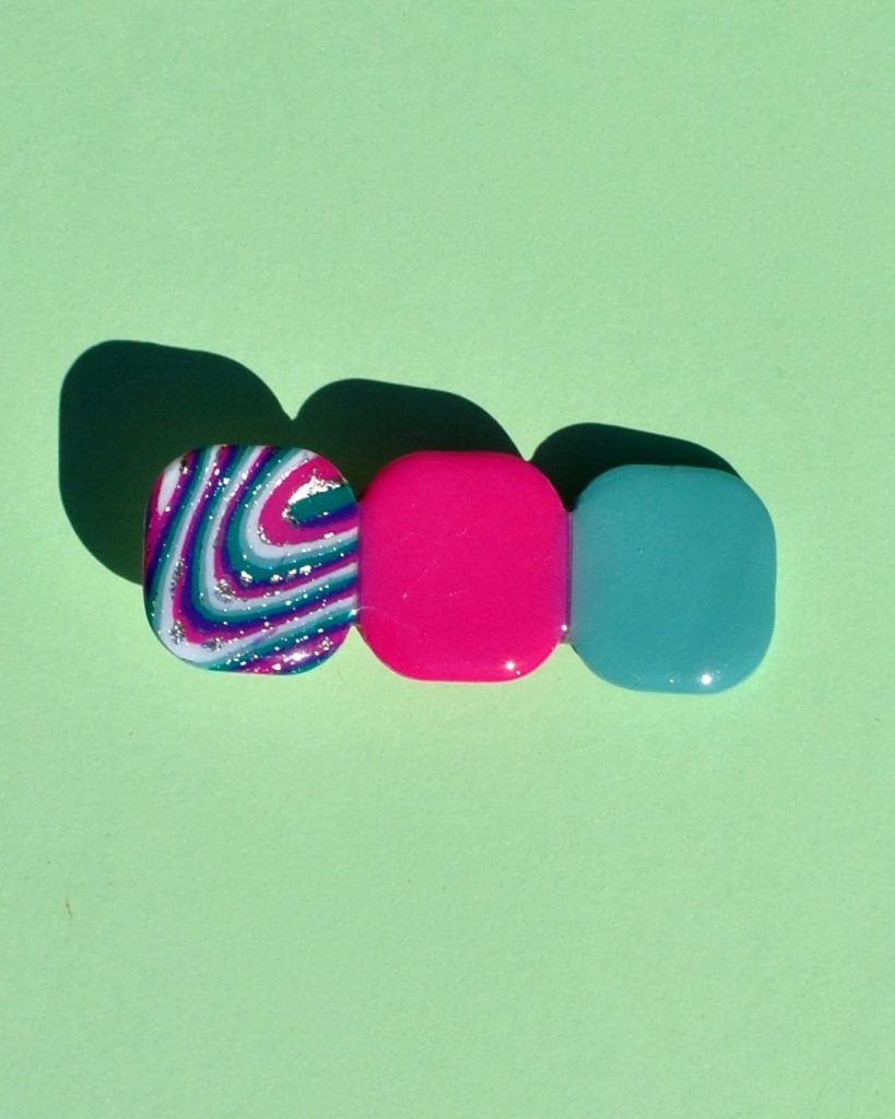 Barrette composée de trois carrés retro, un motif "à la dérive des astres", un rose vif, un vert vague marine.