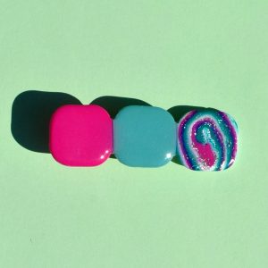 Barrette composée de trois carrés retro, un rose vif, un motif "à la dérive des astres", un vert vague marine.