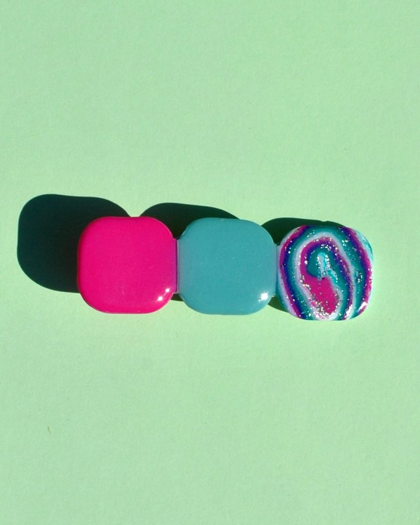 Barrette composée de trois carrés retro, un rose vif, un motif "à la dérive des astres", un vert vague marine.