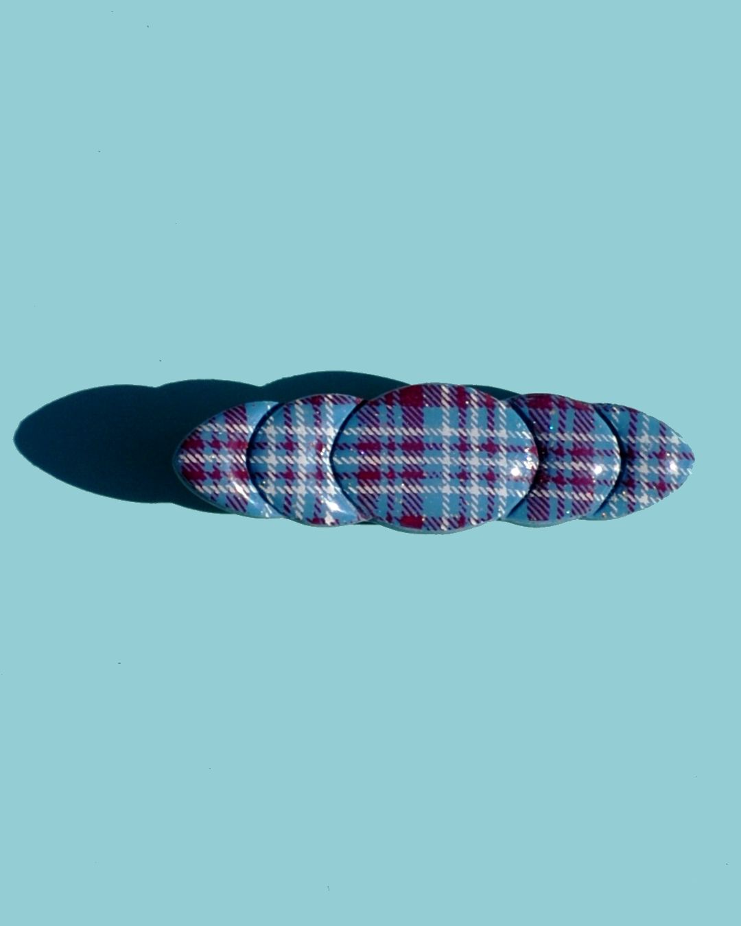 Barrette "ellipse" avec une pleine lune au milieu et des quartiers de lune de part et d'autres. La barrette est au motif carreaux "check" lie-de-vin et blancs.