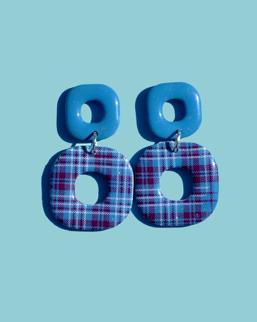 Paire de boucles d'oreilles duo de carrés aux bords arrondis. Un petit carré bleu glacé surmonte un plus gros carré à carreaux "check" lie-de-vin et blancs.