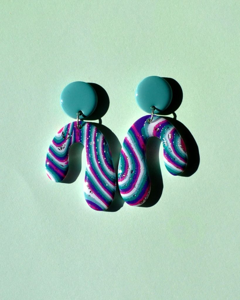 Paire de boucles d'oreilles en forme abstraite motif "à la dérive des astres" surmontée d'une puce ronde vert vague marine unie.