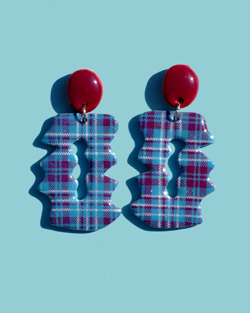 Paire de boucles d'oreilles duo de forme abstraite graphique. Une puce ovale lie-de-vin surmonte un carré irrégulier ajouré, à carreaux "check" lie-de-vin et blancs.
