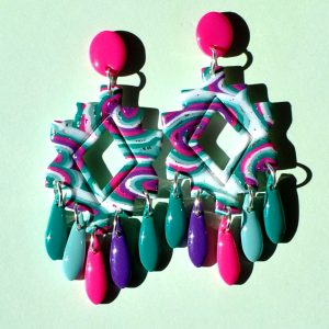 Paire de boucles d'oreilles iconique présentée sur Instagram, en trois partie: une puce rose vif uni qui surmonte une forme géométrique "précolombienne" motif "à la dérive des astres" surmontant cinq pampilles unie (vert vague marine, rose unie, violet et deux pampilles vert émeraude)