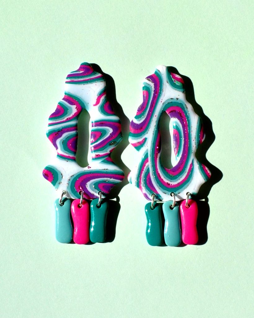 Paire de boucles d'oreilles en forme de "feuille longue" abstraite et ajourée au motif "à la dérive des astres", surmontant trois petites pampilles rectangulaires unie (vert vague marine, rose vif, vert émeraude)