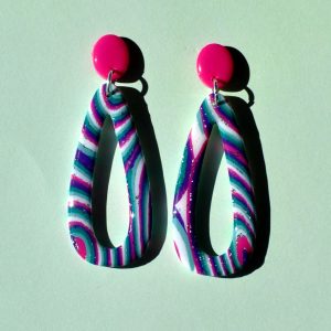 Paire de boucles d'oreilles en forme de "goutte" ajourée au motif "à la dérive des astres", surmontée d'une petite puce ovale rose vif.