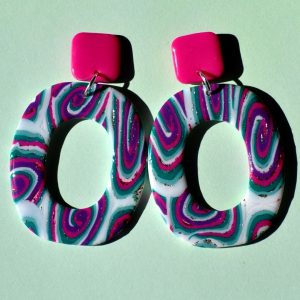 Paire de boucles d'oreilles en forme de "rectangle" rétro aux bords arrondis, ajourée au milieu, au motif "à la dérive des astres", surmontée d'une puce carrée rose vif.