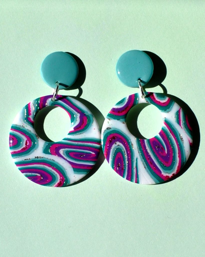 Paire de boucles d'oreilles en forme de rond rétro, ajourée, au motif "à la dérive des astres", surmontée d'une puce ronde unie vert vague marine.