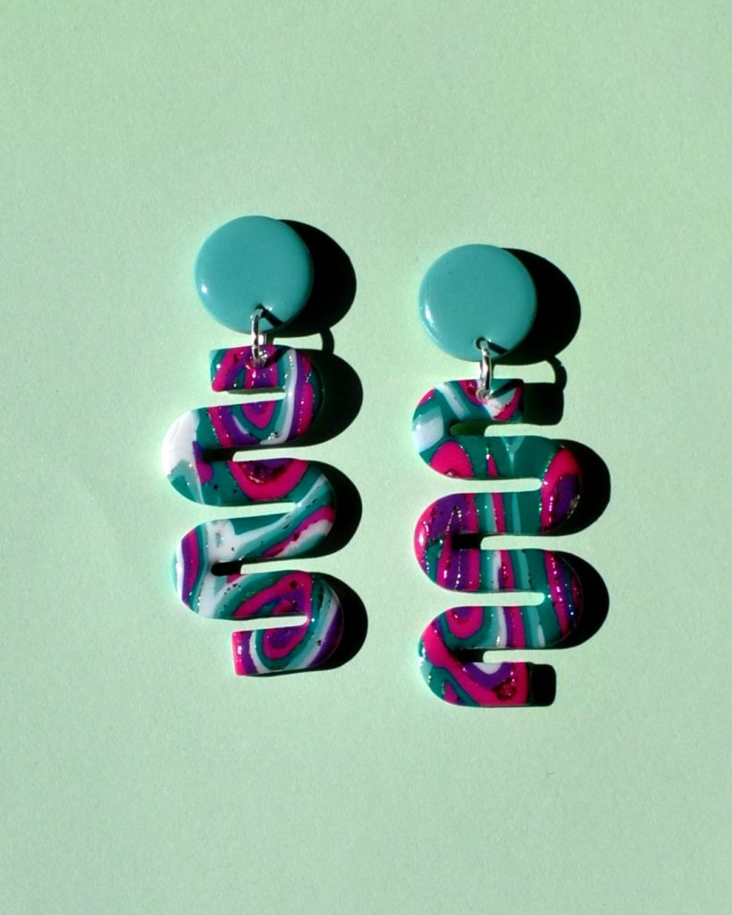 Paire de boucles d'oreilles en forme de "serpent abstrait" motif "à la dérive des astres", surmontée d'une puce ronde unie vert vague marine.