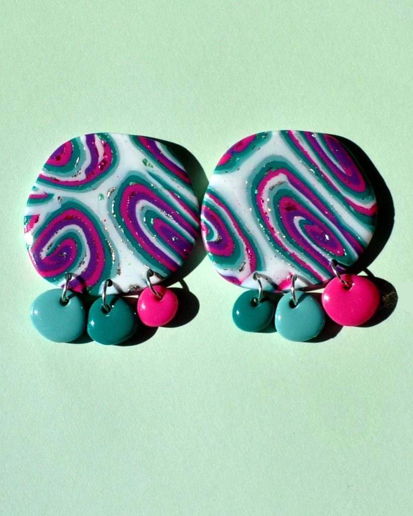 Paire de boucles d'oreilles en deux parties: un gros rond irrégulier motif "à la dérive des astres" surmontant trois petites pampilles ronds irrégulières unies de trois coloris différents (vert vague marine, vert émeraude et rose vif).