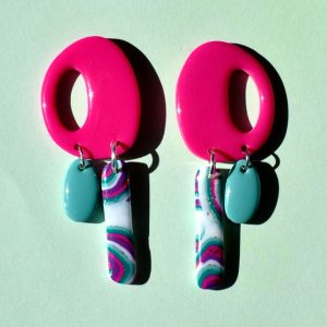 Paire de boucles d'oreilles "ovale" retro rose uni vif, surmontant deux pampilles asymétriques, la plus longue étant un "rectangle" au motif "à la dérive des astres", la plus petite "ovale" unie vert vague marine