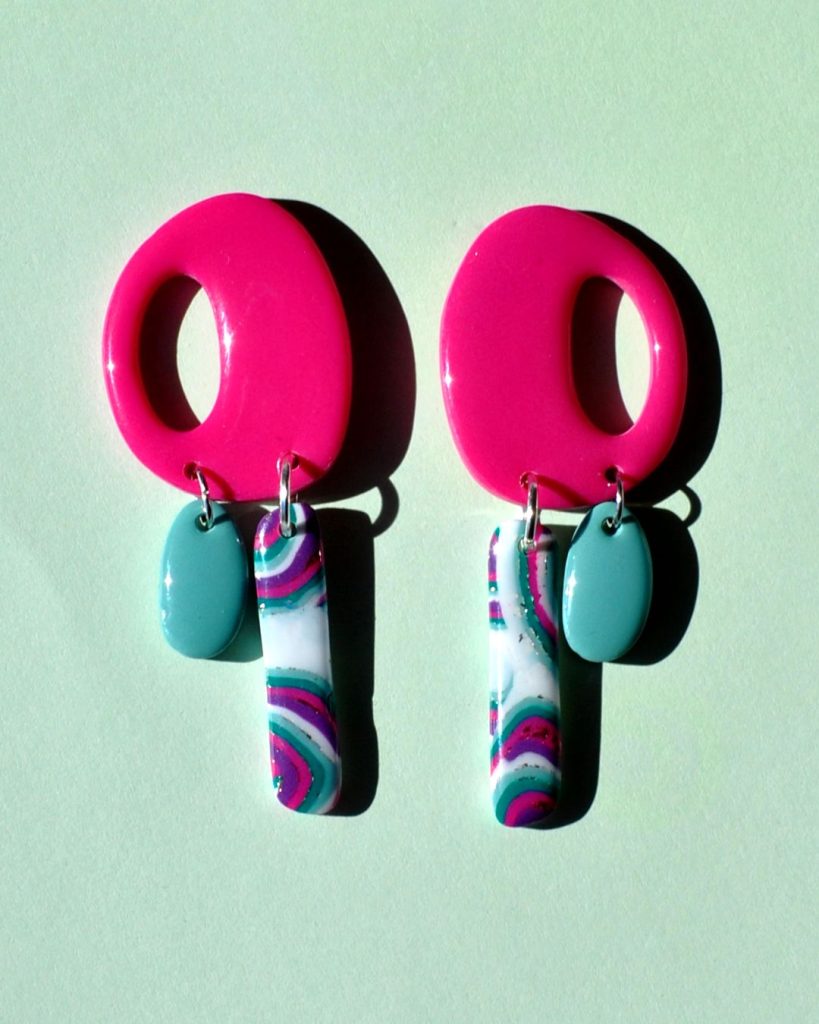 Paire de boucles d'oreilles "ovale" retro rose uni vif, surmontant deux pampilles asymétriques, la plus longue étant un "rectangle" au motif "à la dérive des astres", la plus petite "ovale" unie vert vague marine