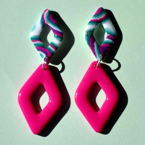 Paire de boucles d'oreilles double losanges: un petit losange motif "à la dérive des astres" surmonte un plus gros losange uni rose vif.