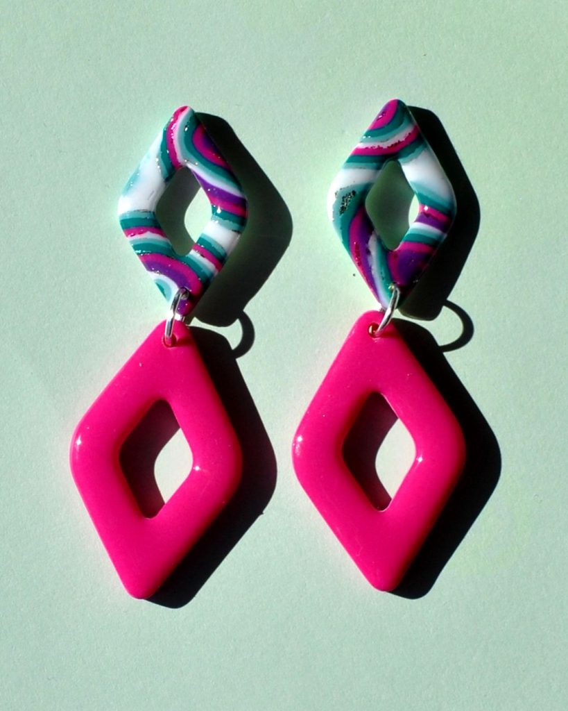 Paire de boucles d'oreilles double losanges: un petit losange motif "à la dérive des astres" surmonte un plus gros losange uni rose vif.