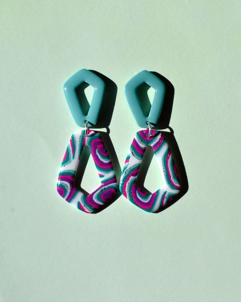 Paire de boucles d'oreilles composée de deux pentagones : un petit pentagone vert vague marine, surmontant un plus grand pentagone inversé au motif "à la dérive des astres".