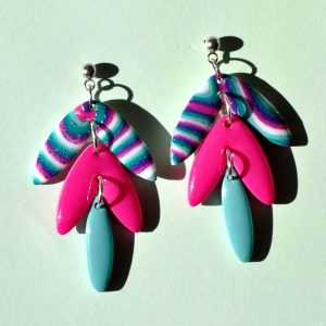 Paire de boucles d'oreilles en quatre parties: une petite puce ronde en acier inoxydable surmonte une forme de "glycine" en trois parties. Le double pétales le plus large, en haut, est au motif "à la dérive des astres". Le double pétales du milieu, de taille moyenne est uni, rose vif. Le dernier pétale unique est uni, vert vague marine.