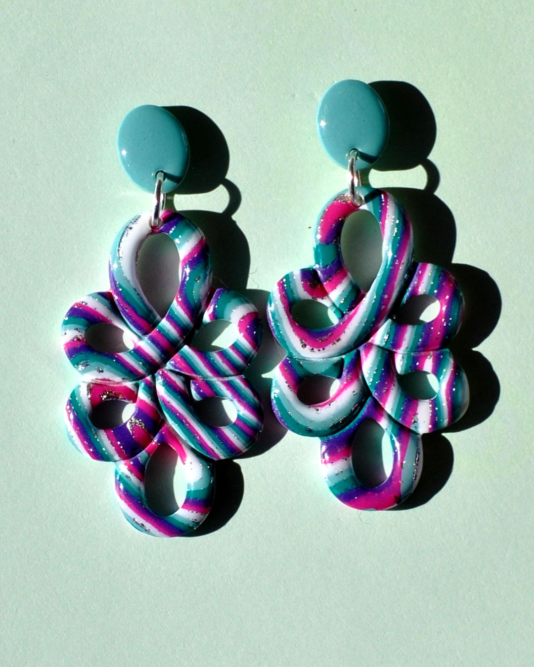 Paire de boucles d'oreilles en deux parties: une puce ovale unie vert vague marine surmonte un "mandala" ajouré au motif "à la dérive des astres".