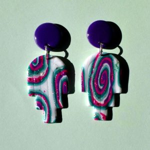 Paire de boucles d'oreilles en deux parties: une puce ronde unie violet profond surmonte un un arc à trois "branches" au motif "à la dérive des astres".