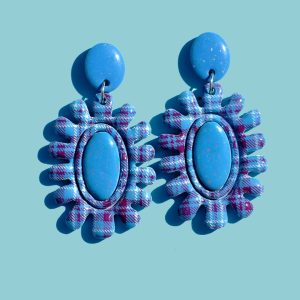 Paire de boucles d'oreilles en forme de fleur abstraite au motif carreaux "check" blancs et lie-de-vin. Le cœur de la "fleur" est un ovale en longueur, en relief uni bleu glacé. La boucle est surmontée d'une puce ovale unie, bleue glacée.
