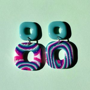 Paire de boucles d'oreilles duo de carrés aux bords arrondis. Un petit carré vert vague marine uni surmonte un plus gros carré motif "à la dérive des astres".