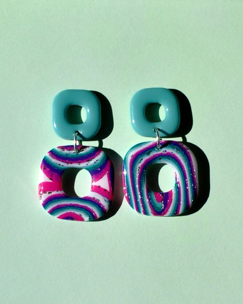 Paire de boucles d'oreilles duo de carrés aux bords arrondis. Un petit carré vert vague marine uni surmonte un plus gros carré motif "à la dérive des astres".
