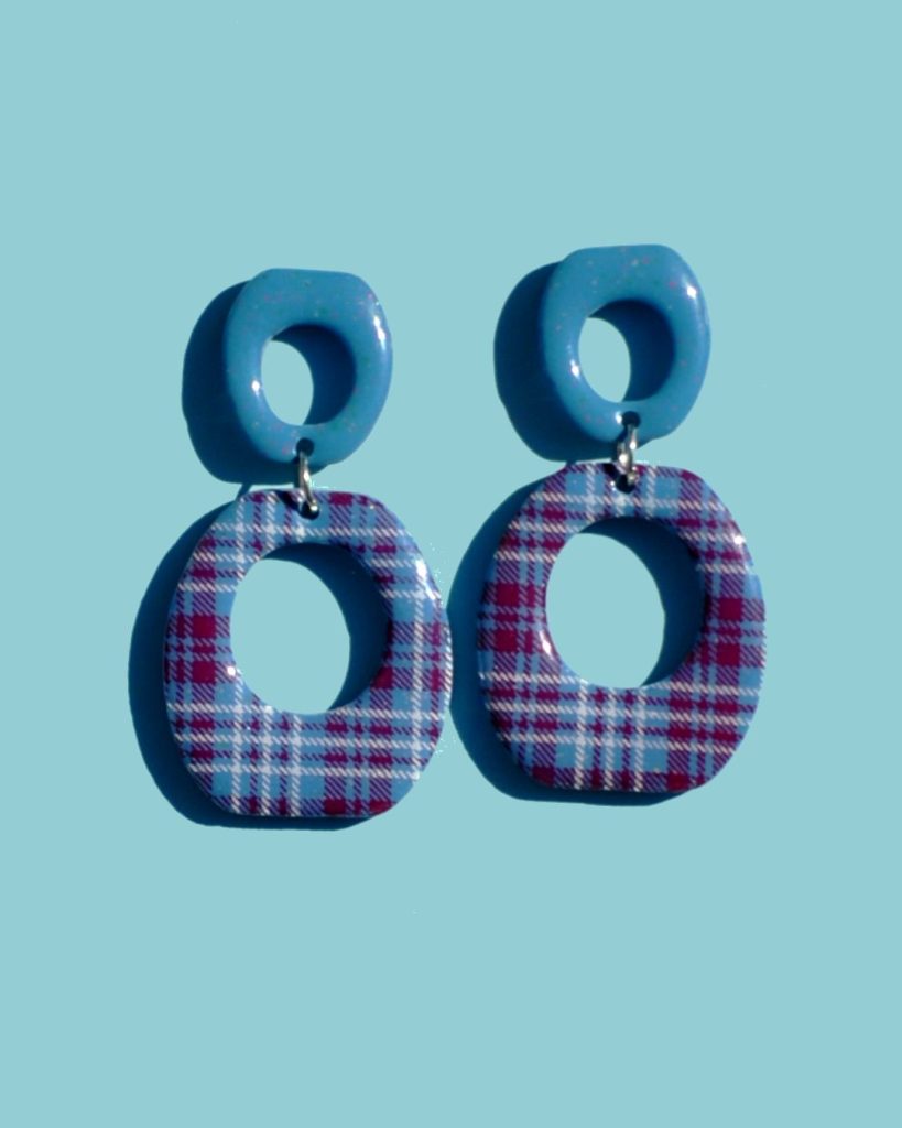 Paire de boucles d'oreilles duo de forme abstraite rétro, ajourée au milieu. Une puce bleue glacée surmonte la même forme inversée, plus grosse à carreaux "check" lie-de-vin et blancs.