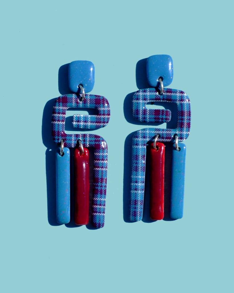 Paire de boucles d'oreilles en 3 parties: une petite puce rectangulaire en longueur bleue givrée, une forme abstraite "précolombienne" à carreaux "check" lie-de-vin et blancs, surmontant deux pampilles, une bleu givrée et une lie-de-vin.