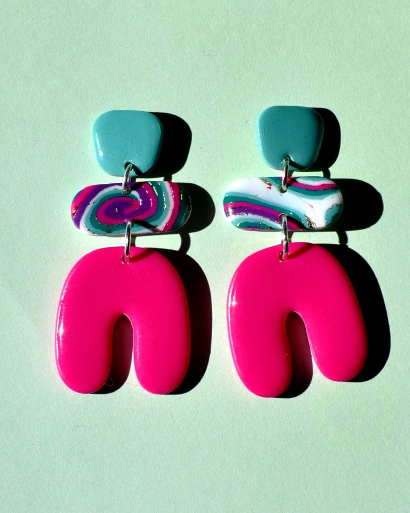 Paire de boucles d'oreilles en trois parties: une puce "carrée" arrondie vert vague marine unie, surmontant un "rectangle" arrondi motif "à la dérive des astres", surmontant un U à l'envers rose vif uni.