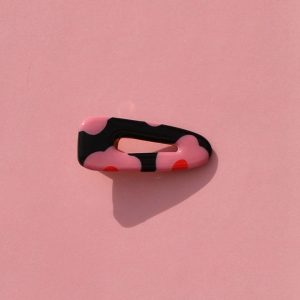 Barrette triangle classique aux bords arrondis, ajourée, au motif à fleurs roses à six pétales à cœur rouge sur fond noir.