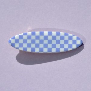 Barrette ellipse forme "planche de surf", au motif damier violet pâle sur fond blanc.