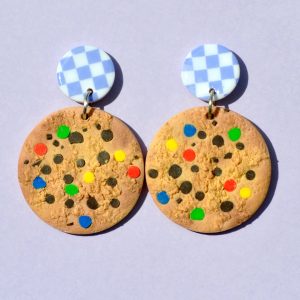 Paire de boucles d'oreilles en forme de cookie géant aux smarties colorées. Une puce en pâte polymère blanche à carreaux violets clairs surmonte la boucle.