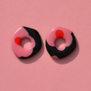 Pampilles interchangeables de "grande" taille en forme de cercle organique irrégulier motif à fleurs roses à six pétales à cœur rouge sur fond noir.