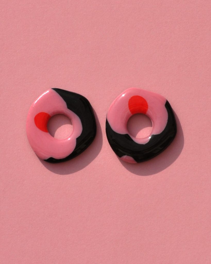 Pampilles interchangeables de "grande" taille en forme de cercle organique irrégulier motif à fleurs roses à six pétales à cœur rouge sur fond noir.