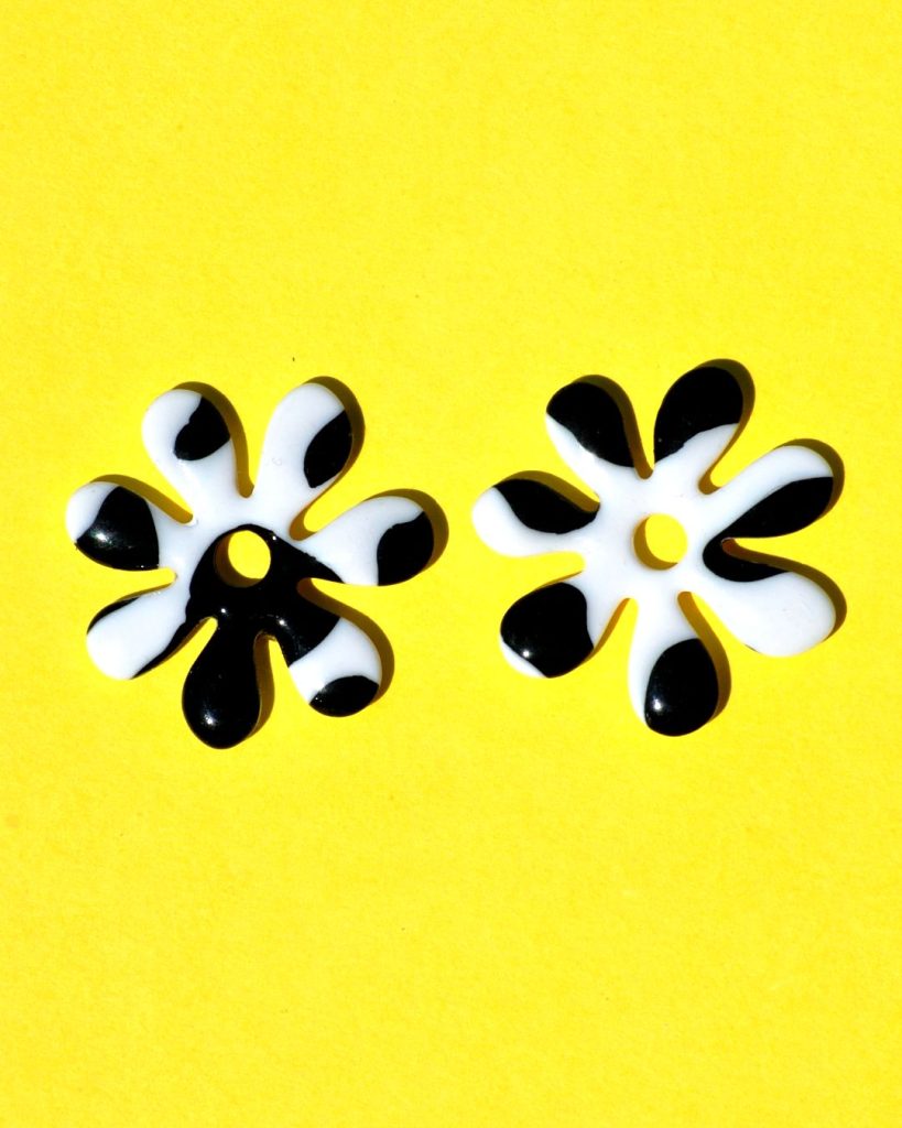 Pampilles interchangeables grande taille en forme de fleurs à sept pétales, motif avec tâches de vache noires sur fond blanc.
