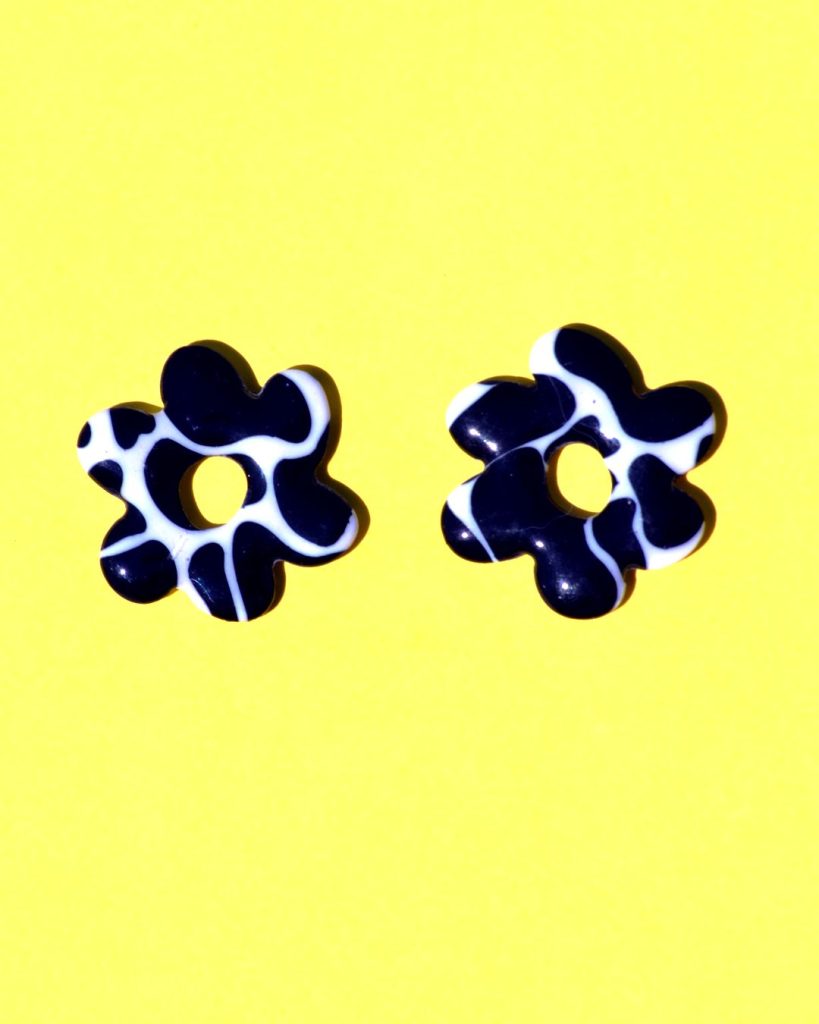 Pampilles interchangeables de "grande" taille en forme de fleurs classiques à six pétales irréguliers, motif avec tâches de vache noires sur fond blanc.