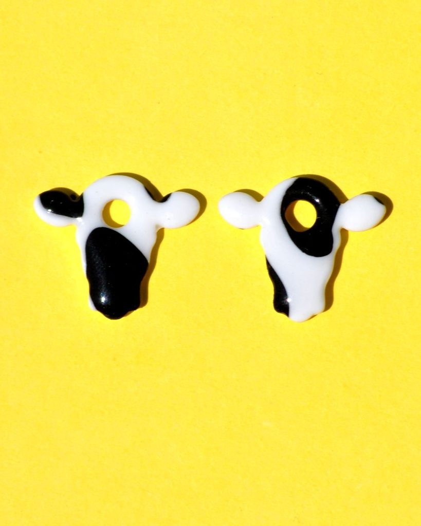 Pampilles interchangeables en forme de petite tête de vache, avec tâches de vache noires sur fond blanc.