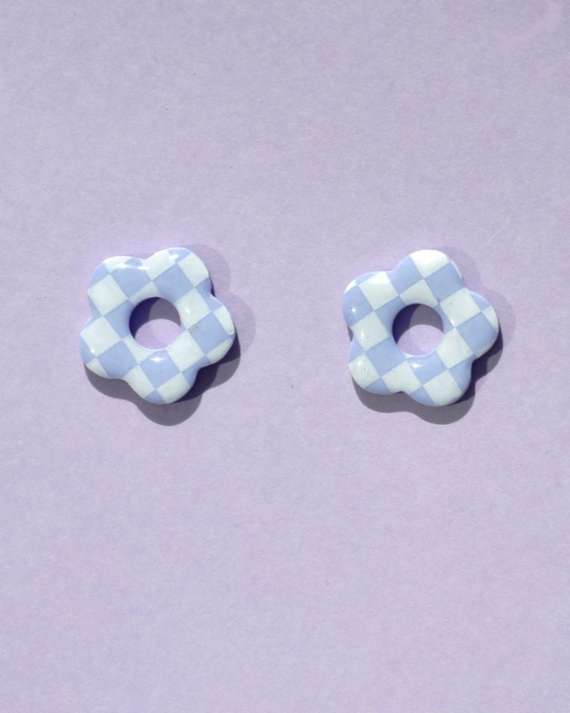 Pampilles interchangeables de taille moyenne en forme de fleurs à cinq pétales, motif damier blanc sur fond violet pâle.