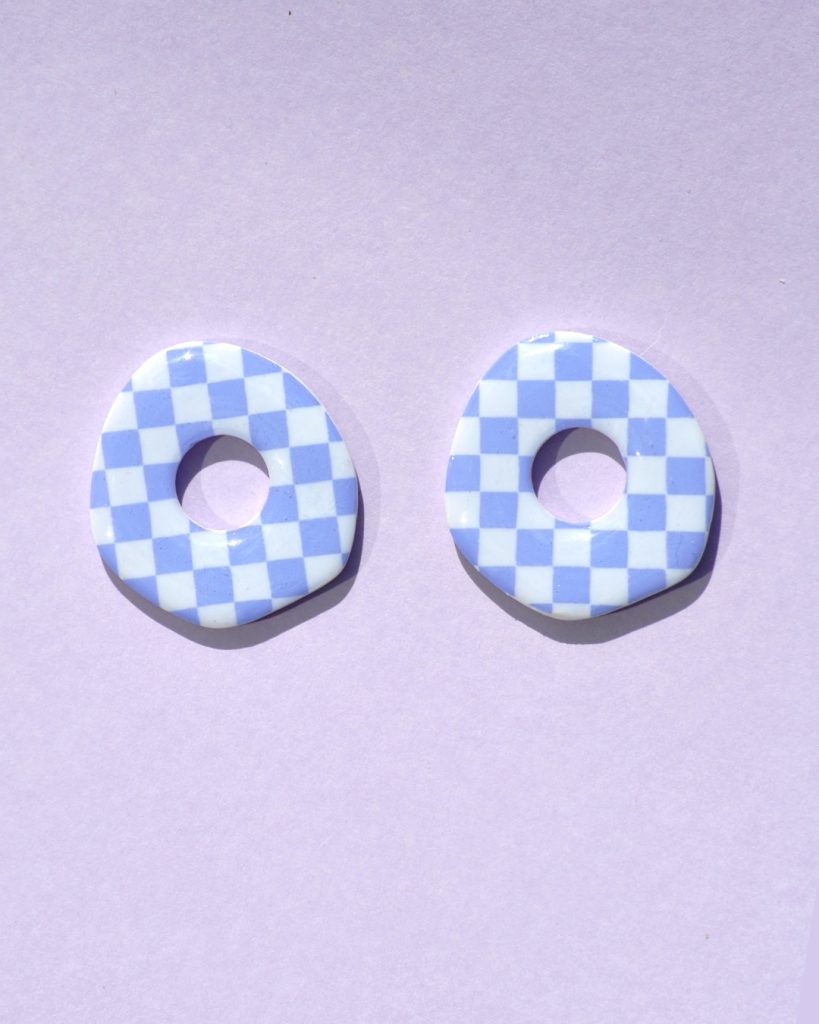 Pampilles interchangeables de "grande" taille en forme de cercle organique irrégulier motif damier violet pâle sur fond blanc.