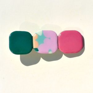 Barrette composée de trois carrés retro, un vert foncé, un motif floral et un rouge-rose.