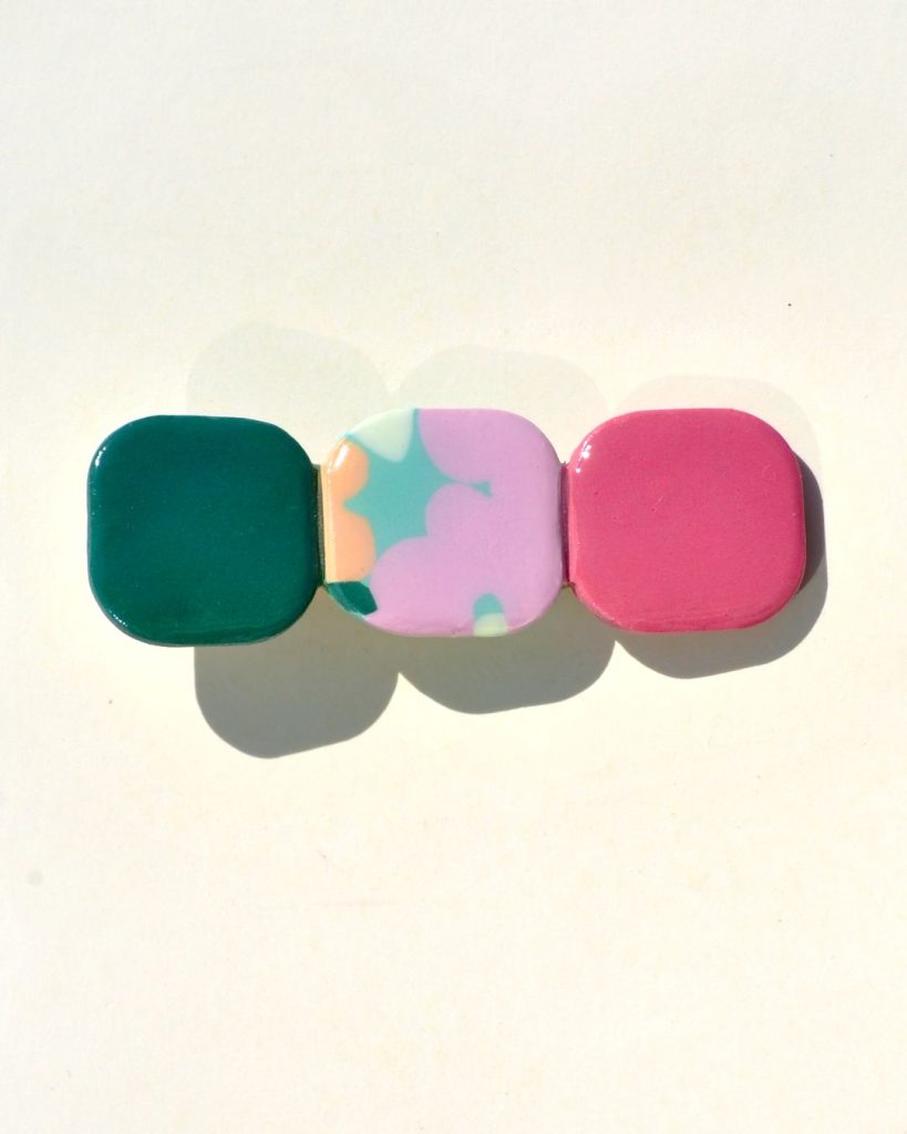 Barrette composée de trois carrés retro, un vert foncé, un motif floral et un rouge-rose.