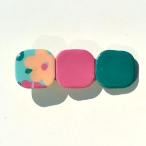 Barrette composée de trois carrés retro, un motif floral, un rouge-rose et un vert foncé.
