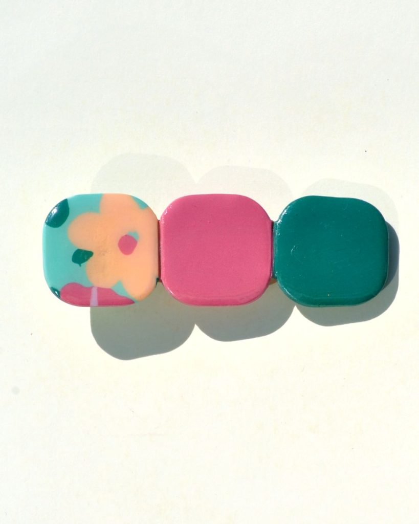 Barrette composée de trois carrés retro, un motif floral, un rouge-rose et un vert foncé.