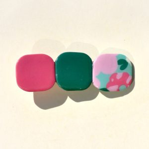 Barrette composée de trois carrés retro, un rouge-rose, un vert foncé et un motif floral.