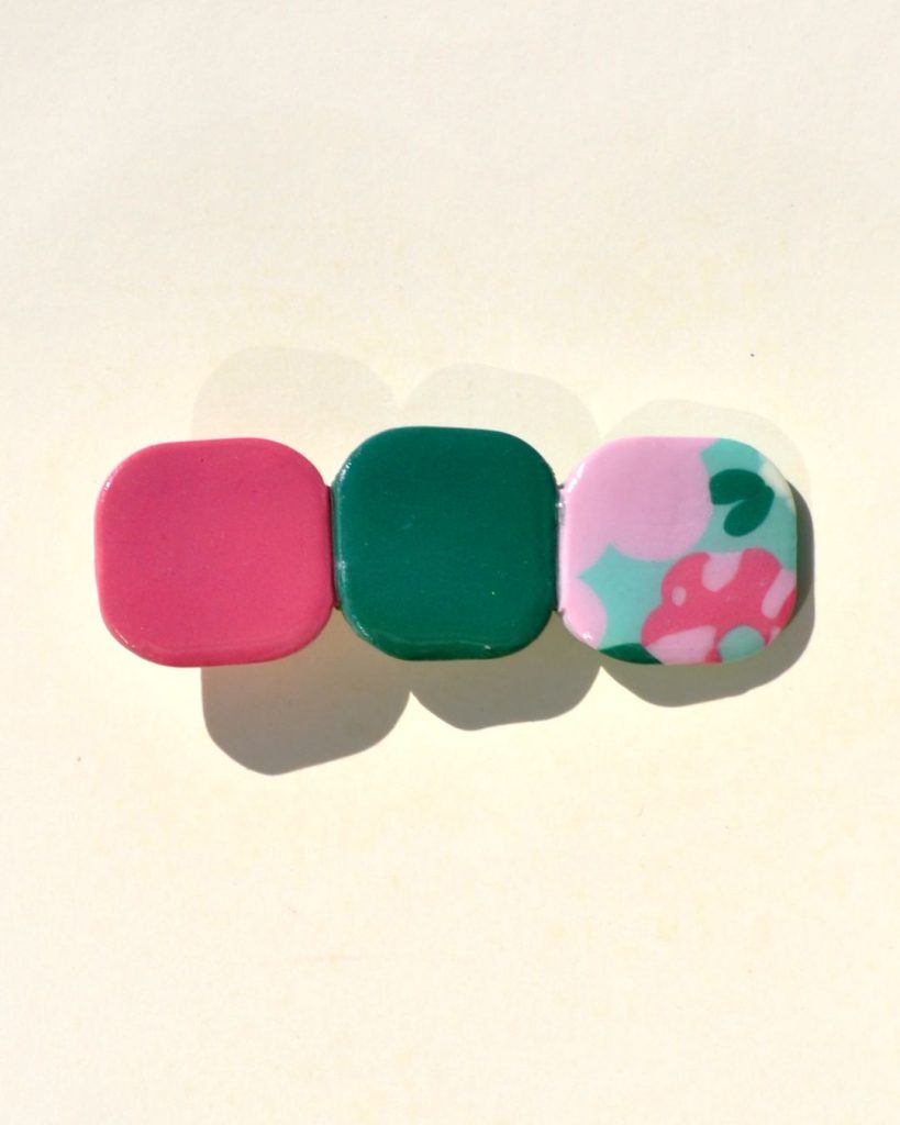 Barrette composée de trois carrés retro, un rouge-rose, un vert foncé et un motif floral.