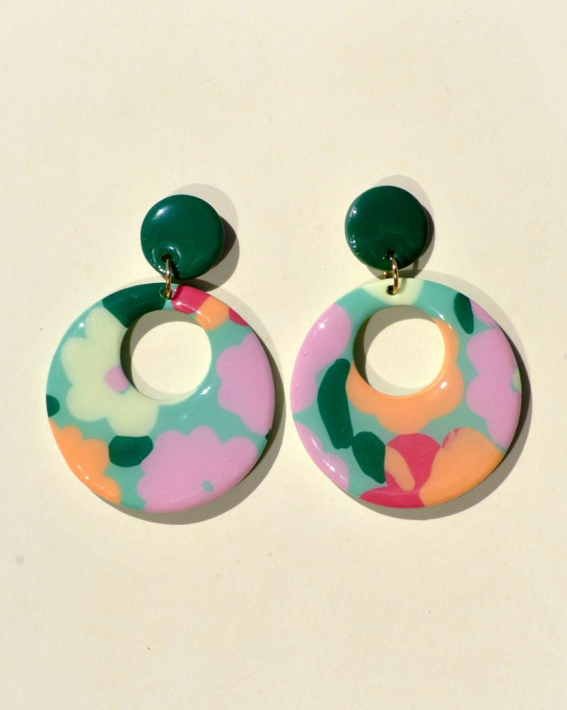 Paire de boucles d'oreilles en forme de rond rétro, ajourée, au motif floral printanier, surmontée d'une puce ronde unie vert foncé.