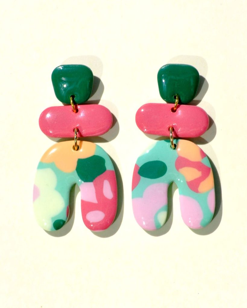 Paire de boucles d'oreilles en trois parties: une puce "carrée" arrondie vert foncé, surmontant un "rectangle" arrondi rose-rouge uni, surmontant un U à l'envers motif floral printanier.