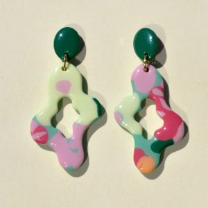 Paire de boucle d'oreilles abstraite au motif floral printanier, surmontée d'une puce ovale unie verte foncée.