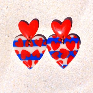 Paire de boucles d'oreilles deux cœurs superposés: la puce est un petit cœur rouge qui surmonte un autre cœur au motif marinière avec des cœurs rouges.