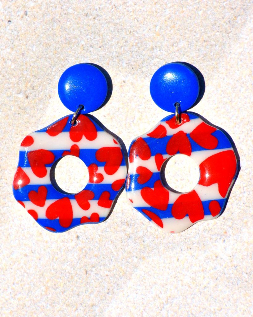 Paire de boucles d'oreilles en forme de "fleurs" abstraites motif marinière cœurs rouges, surmontées d'une puce ronde unie bleue éclatant.